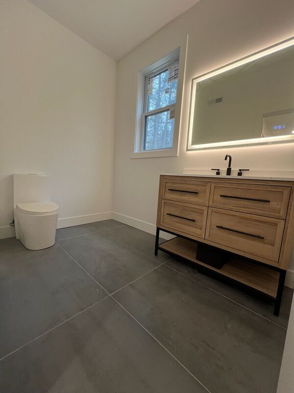 Bathroom with floating wood vanity and backlit mirror