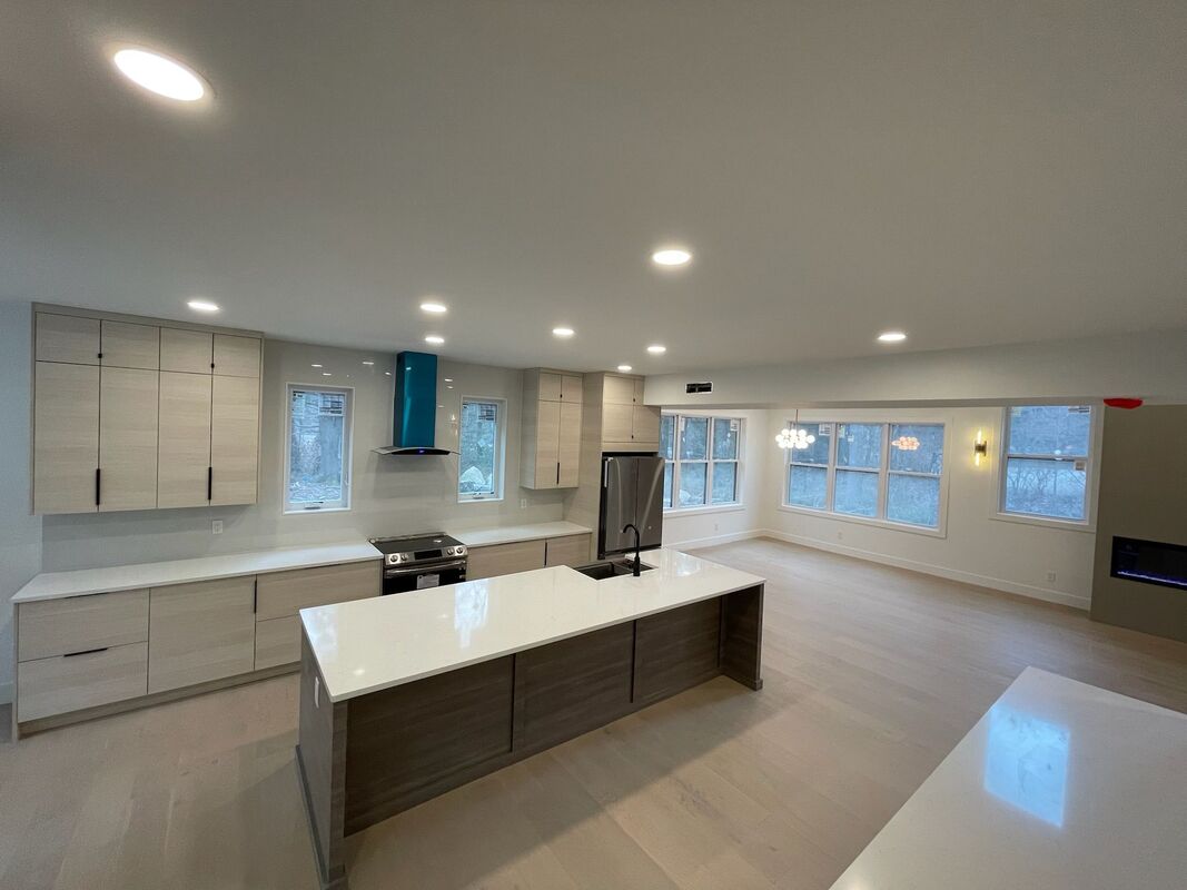 Light-wood kitchen with quartz island opening to a living area